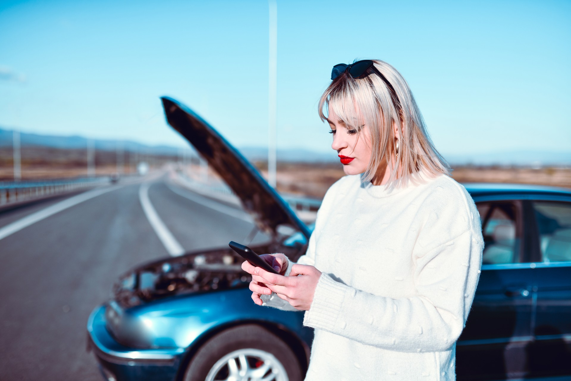 Female Using Smartphone To Call Family After Car Breaks Down On Road