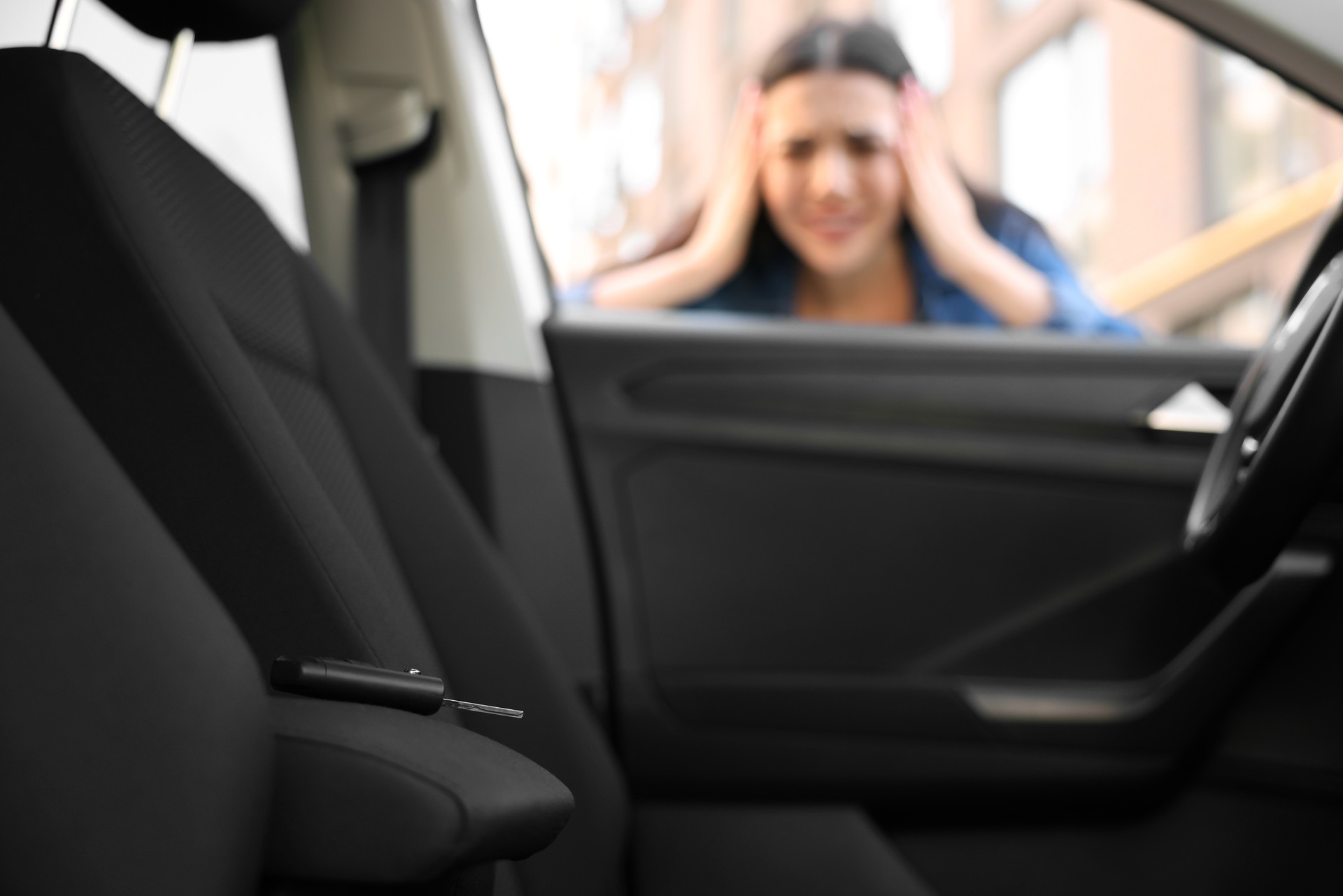 Automobile lockout, key forgotten inside, selective focus. Emotional woman looking through car window